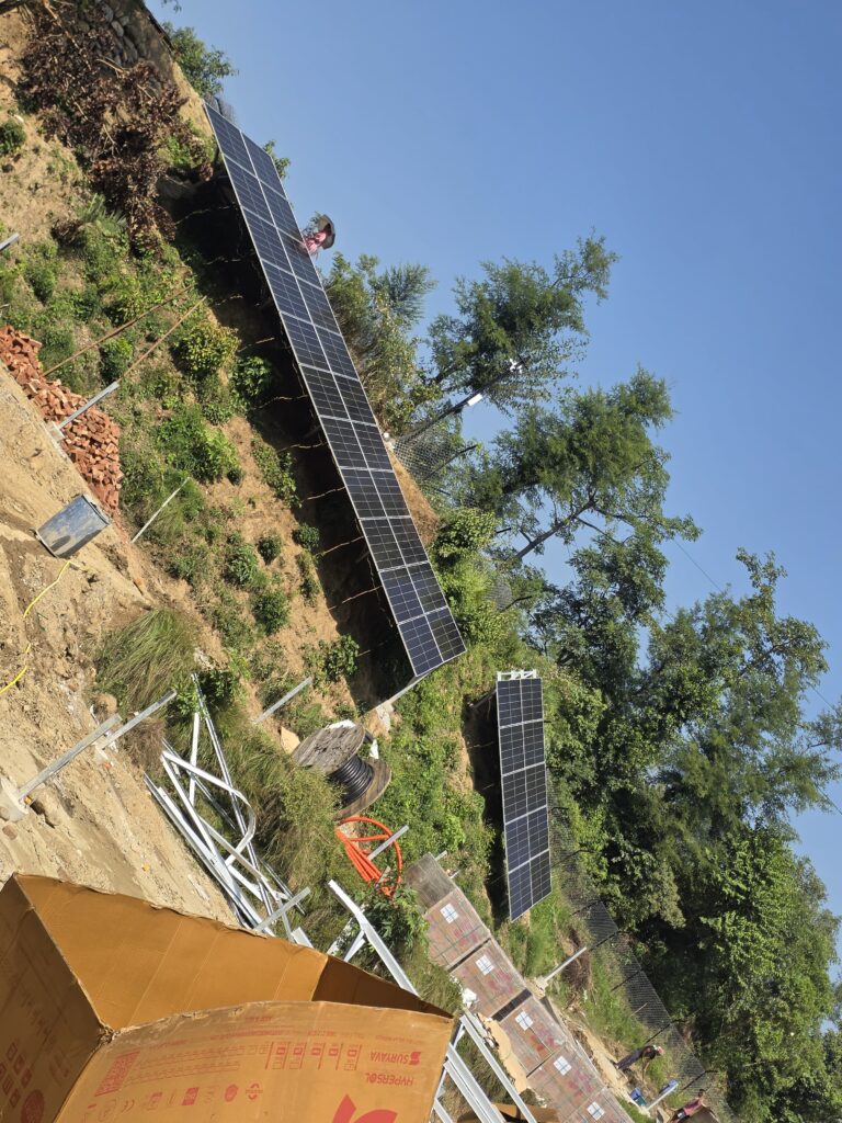 Solar panel rows and mounting materials on sloping ground.