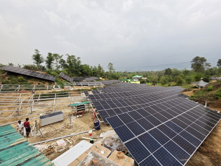 Solar panel rows beside mounting structures and the on-site team.